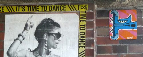 Œuvre street art de l'artiste graffeur Oré. Serpent à plumes, Quetzalcóatl, collé dans les rues de Berlin, à côté d'une affiche avec une femme qui danse.