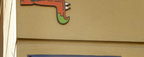 Œuvre street art de l'artiste graffeur Oré. Serpent à plumes, Quetzalcóatl, collé à Athènes. Au dessus d'une plaque de rue