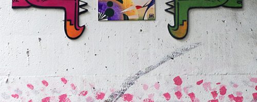 Œuvre street art de l'artiste graffeur Oré. 2 Serpent à plumes, Quetzalcóatl, collés dans les rues de Tokyo. Avec une personne passant sous un parapluie.