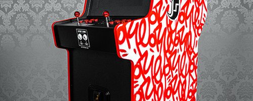 Borne Jeu Artcade peint. Œuvre street art de l'artiste graffeur Oré. Signatures Graffiti rouges et pochoirs noirs de Quetzalcóatl. Vue de coté.