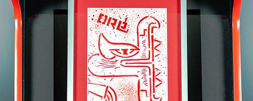 Borne Jeu Artcade peint. Œuvre street art de l'artiste graffeur Oré.Vue de face. Sérigraphie avec un quetzalcóatl sur l'écran.